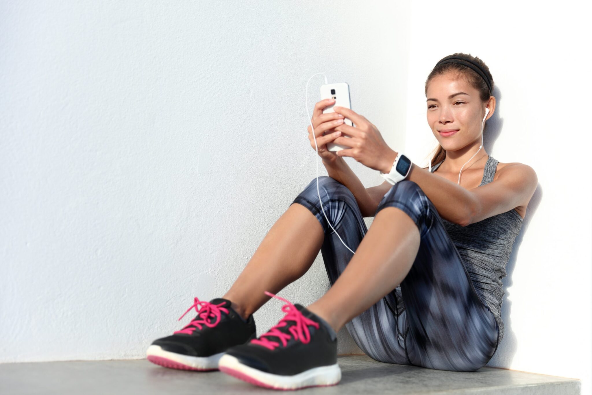 Mobile gym app truself sporting club san diego gym Sportswoman listening to music using phone app and smartwatch fitness tracker